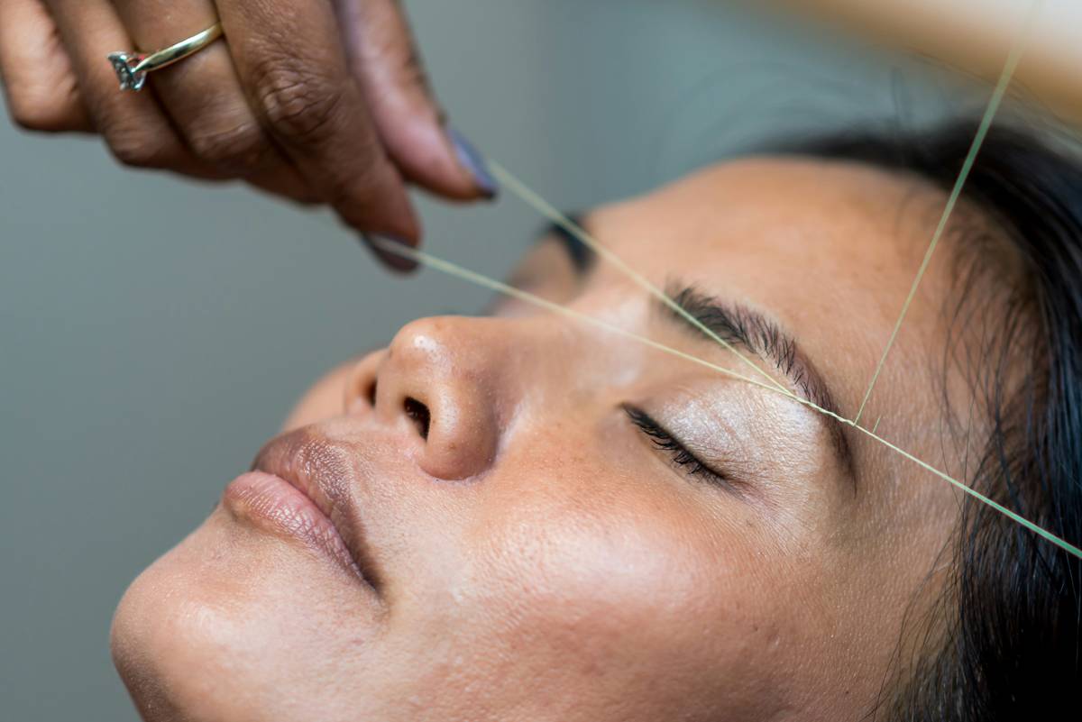 woman applying eyebrow tinting product with angled spoolie for even coverage